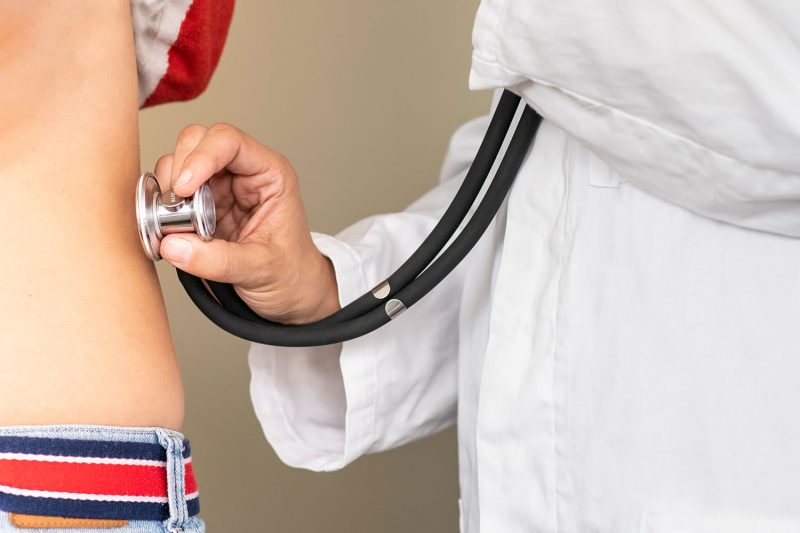 Arzt oder Ärztin untersucht eine Patientin oder einen Patienten mit dem Stethoskop, Detailaufnahme